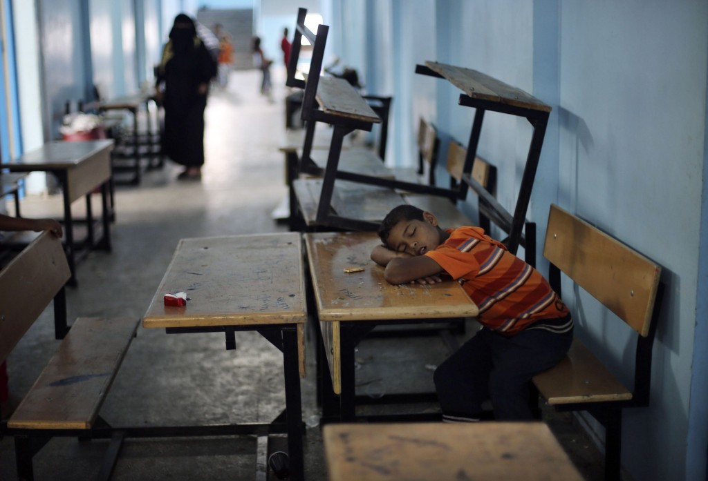 A Palestinian boy, who fled his family's house following an Israeli ground offensive, sleeps as he stays at a UN-run school in Rafah